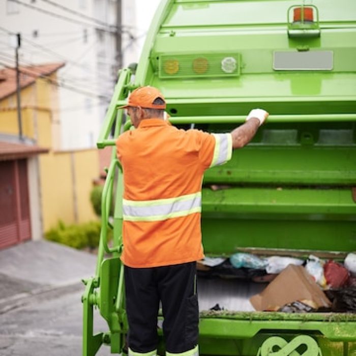 onward-garbage-collection-worker-riding-back-garbage-truck_590464-10920